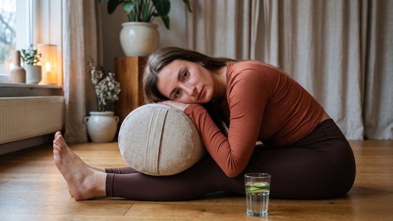 Tanya resting forward over a bolster in a supported seated pose